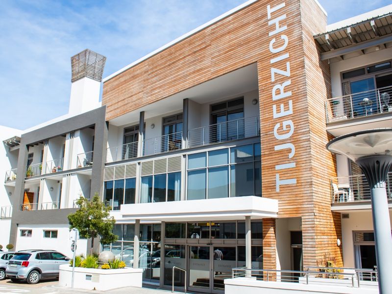 Modern retirement village entrance featuring timber cladding, glass facade, and balconies with stainless steel balustrades.