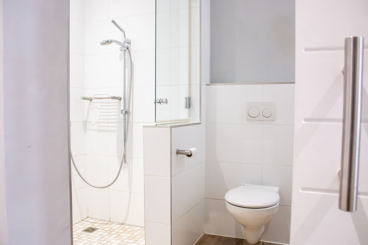 Modern bathroom featuring a walk-in shower with glass screen and a wall-mounted toilet with integrated dual-flush system.