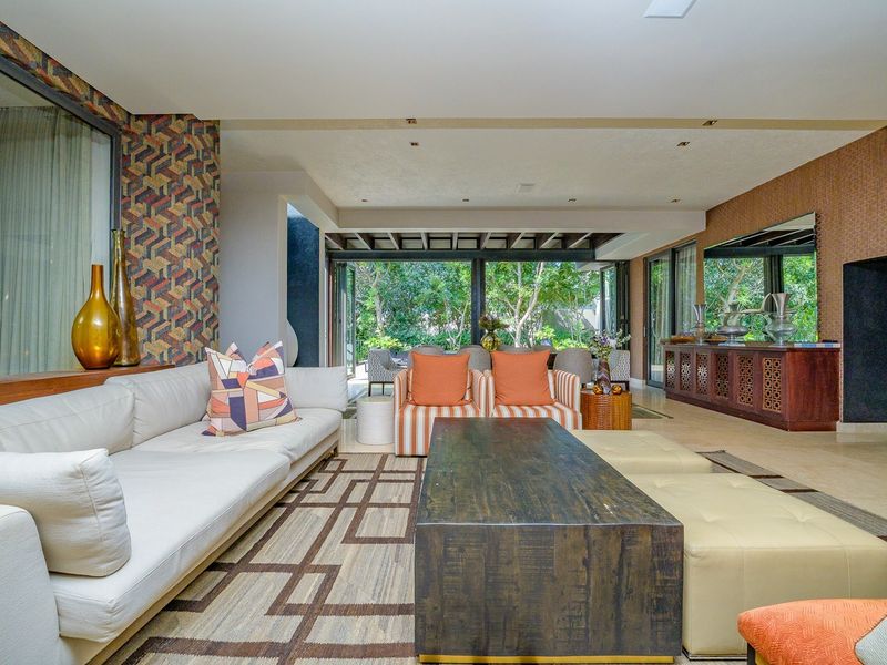 Spacious open-plan living area featuring large sliding glass doors that provide seamless indoor-outdoor flow, recessed lighting, and decorative wallpaper finishes.