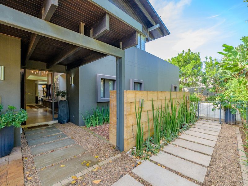 Modern front entrance featuring a timber pergola, stone cladding feature wall, and a clean paved walkway leading to the main door.