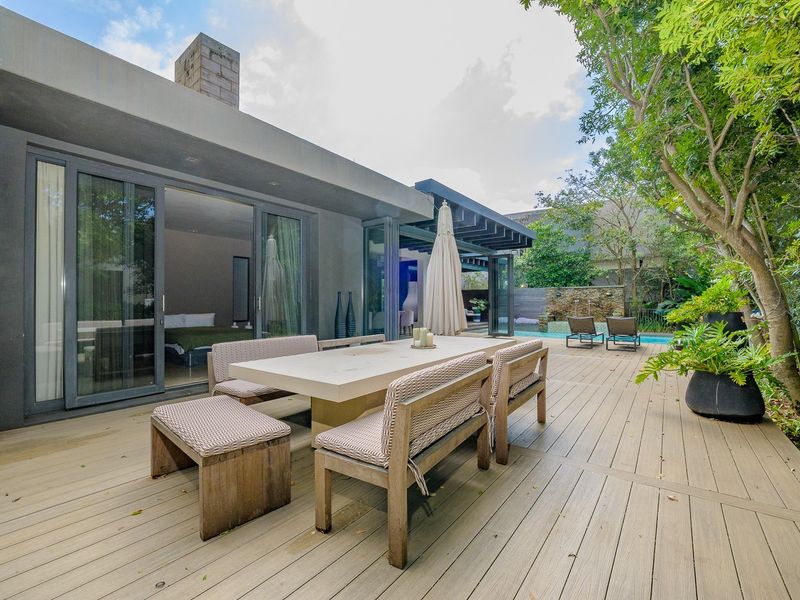 Spacious outdoor timber deck featuring a covered patio area, direct access to the interior via sliding glass doors, and a view of the swimming pool.