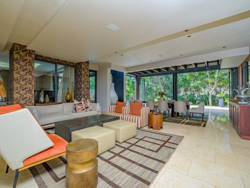 Spacious open-plan living and dining area featuring stone flooring, recessed lighting, and large sliding glass doors that open to the garden.