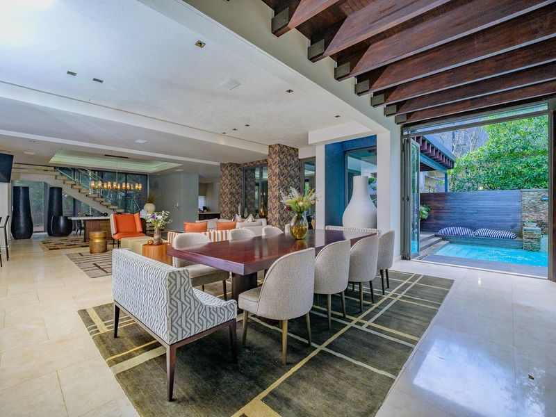 Spacious open-plan living and dining area featuring exposed timber beams, stone flooring, and seamless indoor-outdoor flow to a private pool area via bi-fold doors.