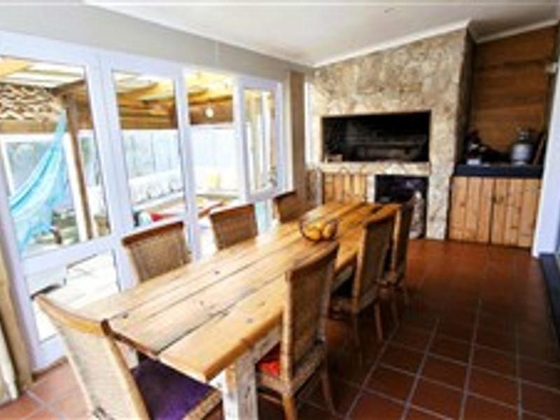 Enclosed patio area featuring a built-in braai with stone cladding, tiled flooring, and large sliding glass doors providing access to the outdoor space.