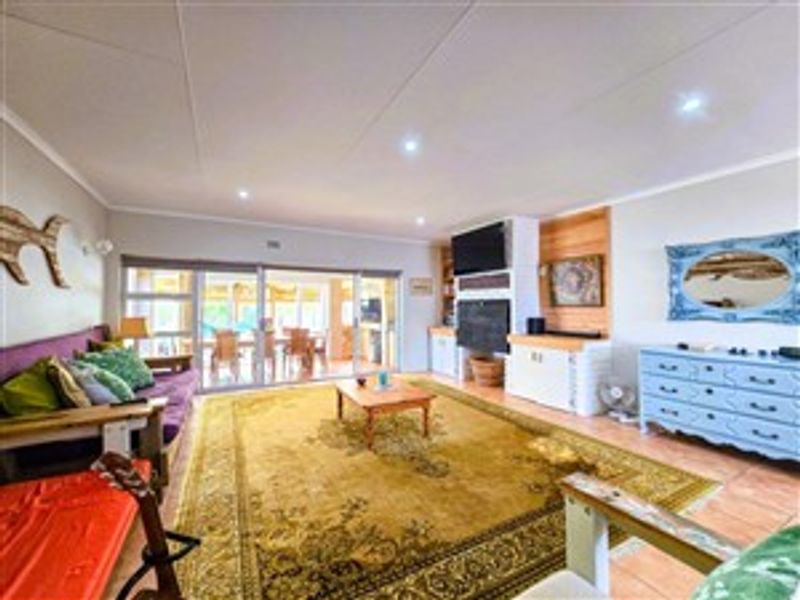 Spacious living room featuring tiled flooring, recessed downlights, and large sliding glass doors that provide access to the outdoor patio area.