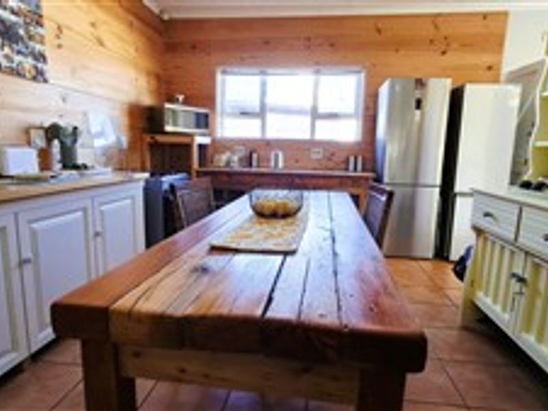A rustic kitchen featuring timber wall paneling, tiled flooring, and built-in cabinetry with a wooden countertop.