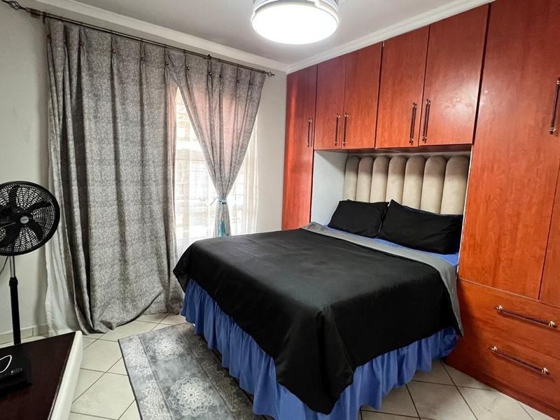 A bedroom featuring built-in wooden cupboards and tiled flooring, providing functional storage and a neutral base for interior design.