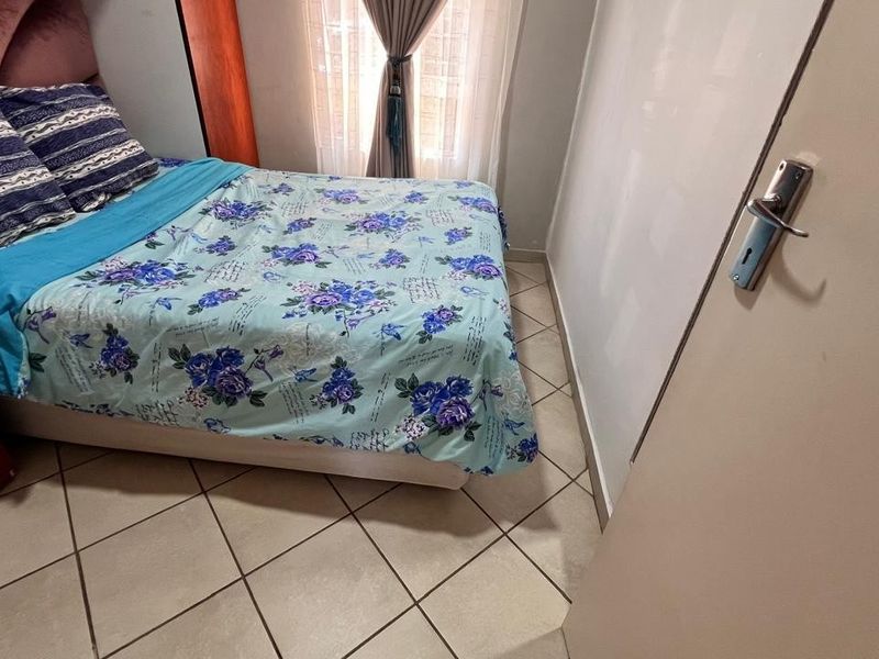 A compact bedroom featuring tiled flooring and a built-in wardrobe, providing functional storage space.
