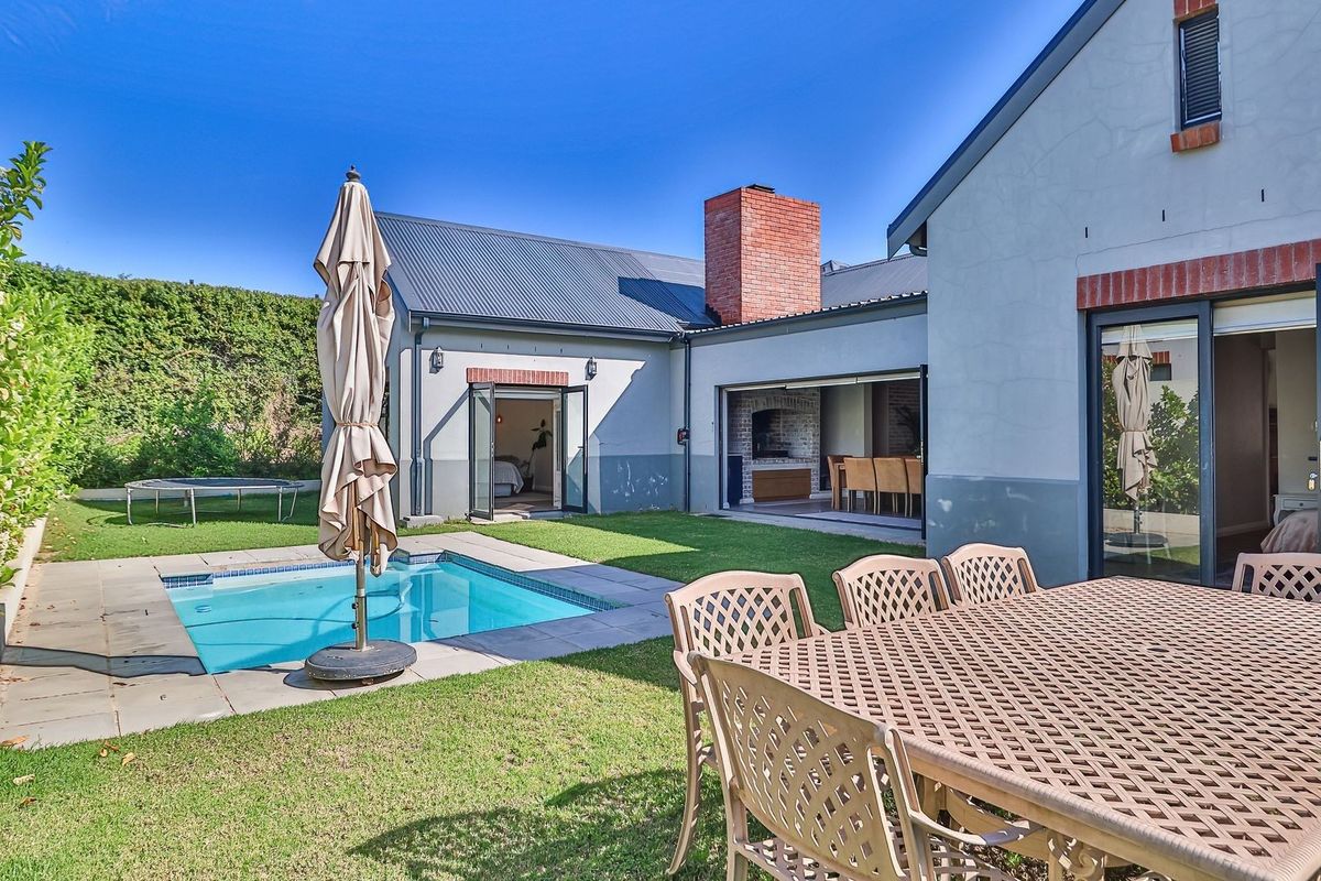 Rear exterior view featuring a swimming pool, paved patio area, and seamless indoor-outdoor flow through large sliding glass doors.