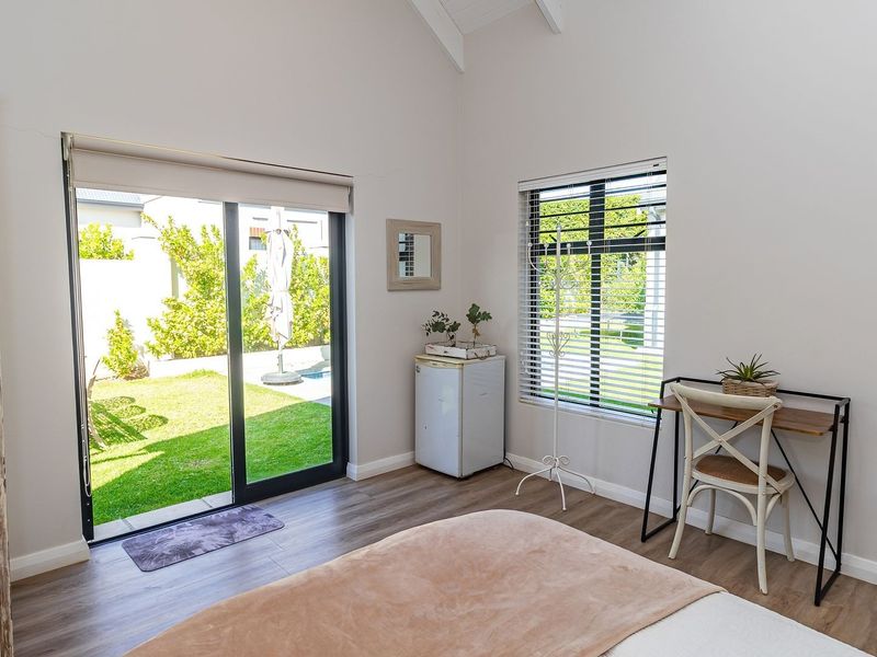 Bright bedroom featuring vaulted ceilings, laminate flooring, and a sliding glass door providing direct access to the garden.
