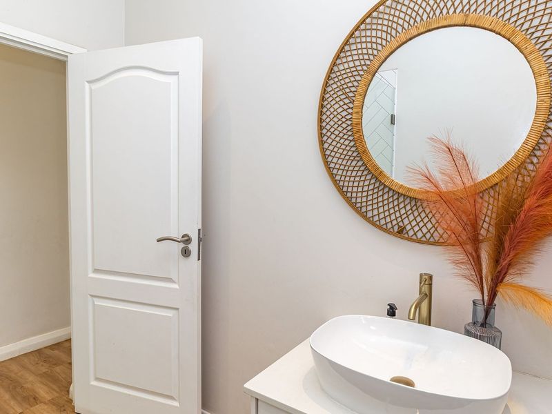 A modern bathroom featuring a white vessel sink with a brass faucet mounted on a vanity cabinet.
