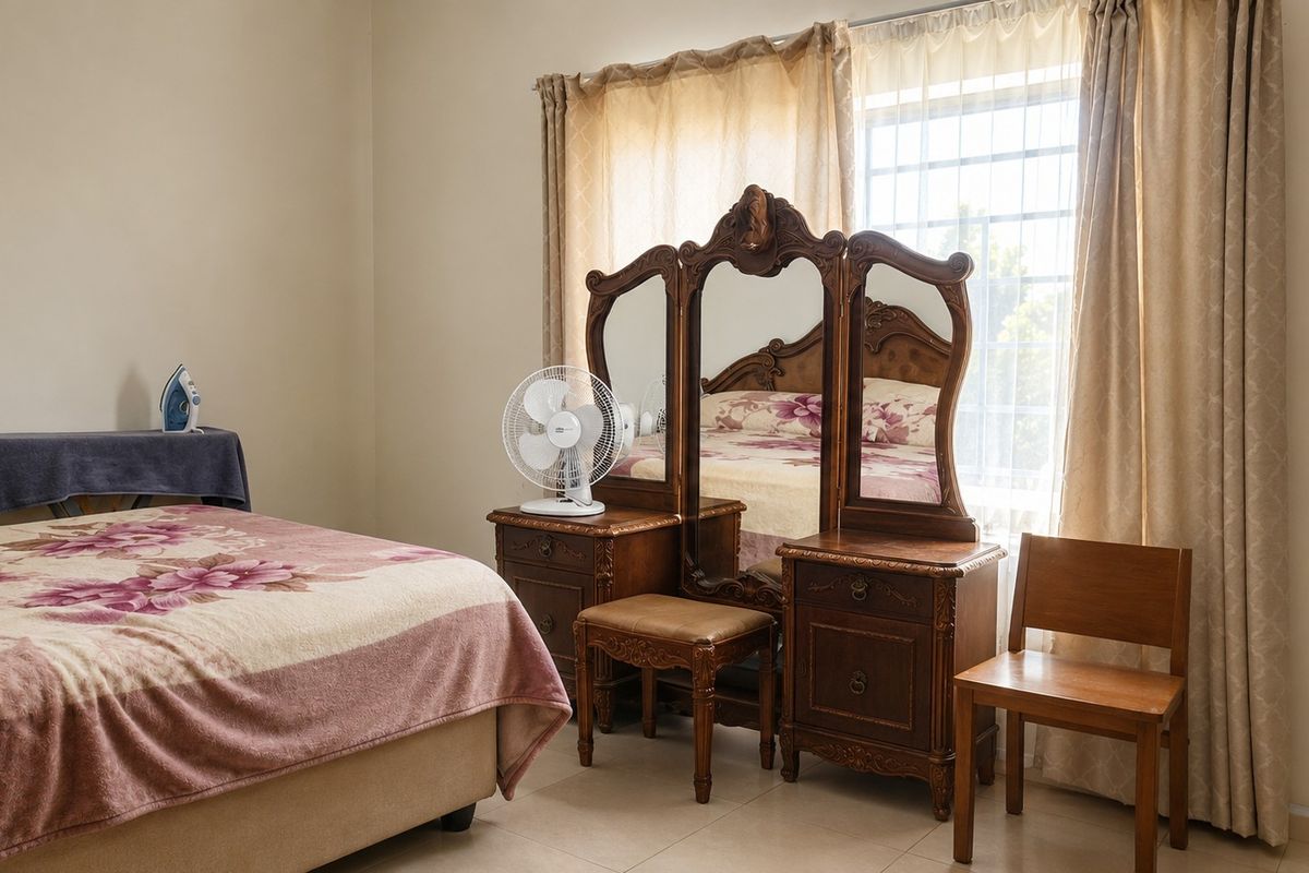 A well-lit bedroom featuring tiled flooring and a window fitted with security bars, providing a functional and comfortable living space.