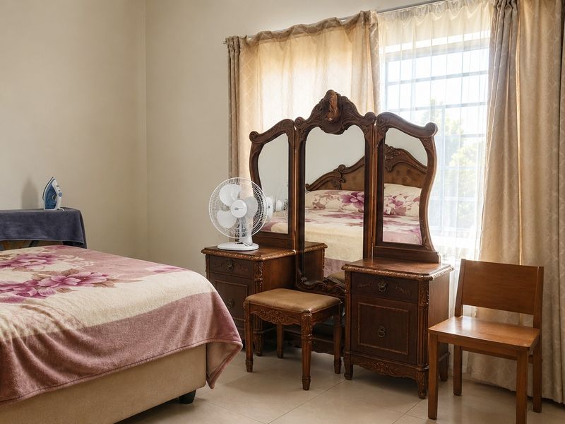 A well-lit bedroom featuring tiled flooring and a window fitted with security bars, providing a functional and comfortable living space.