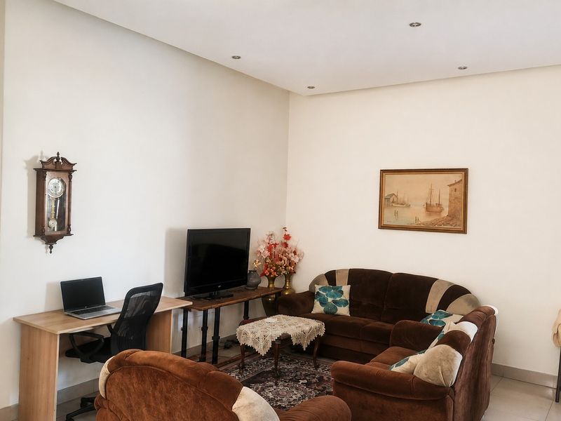 A living room featuring neutral walls, recessed downlighting, and tiled flooring, providing a functional and well-lit space for relaxation.