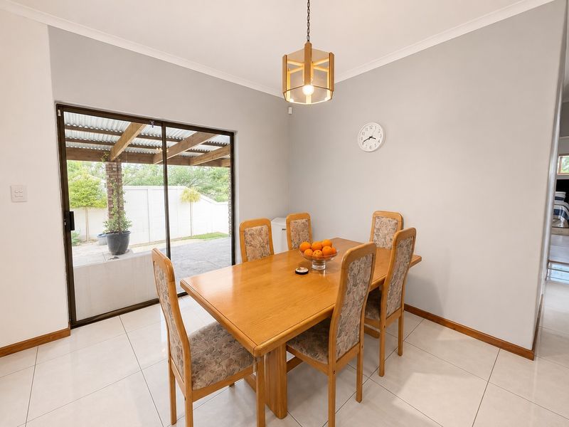 A bright dining room featuring tiled flooring, a central pendant light, and a sliding glass door providing access to the outdoor patio area.