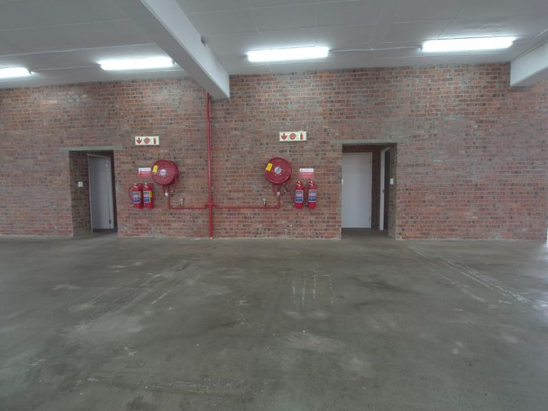 Spacious industrial utility area featuring exposed brick walls, concrete flooring, and integrated fire safety equipment including hose reels and extinguishers.