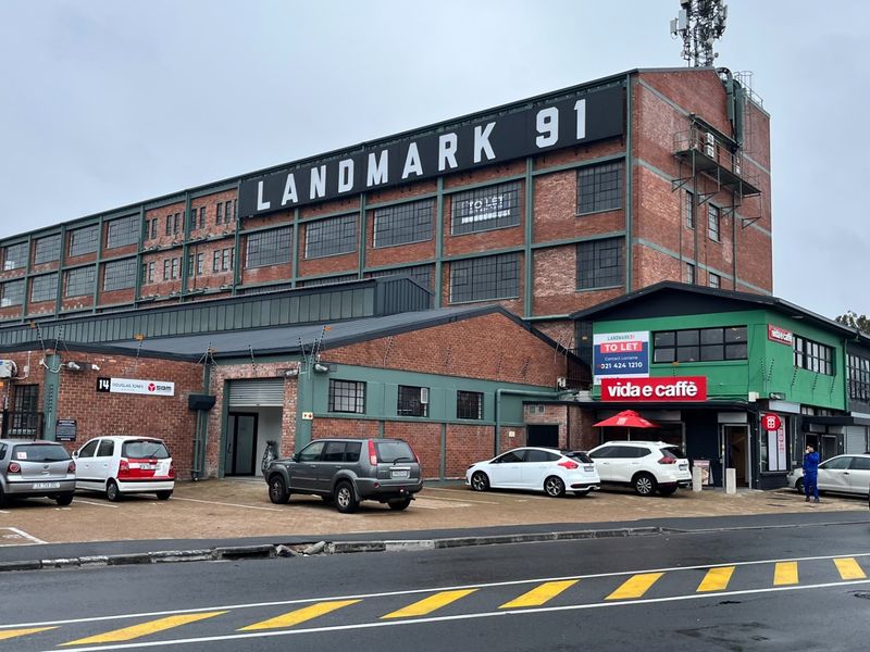 Front view of the Landmark 91 industrial building featuring a multi-story brick facade, metal roofing, and an integrated parking area with commercial signage.
