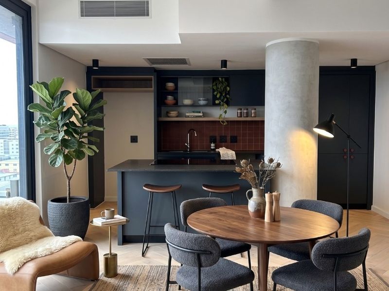 Modern open-plan living and dining area featuring a sleek kitchen with dark cabinetry, a central island, and high-end finishes throughout.