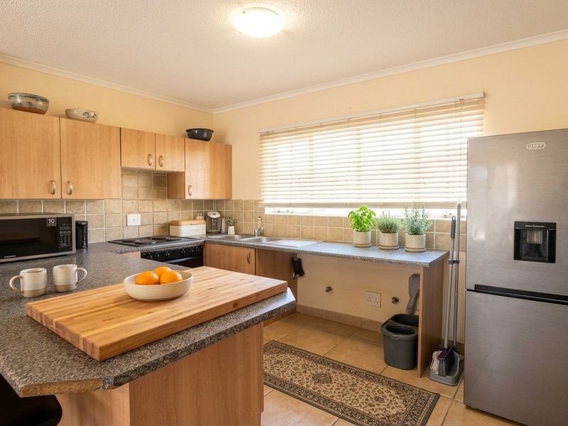 A functional kitchen featuring laminate cabinetry, granite countertops, tiled backsplash, and built-in cooking appliances with a breakfast bar area.