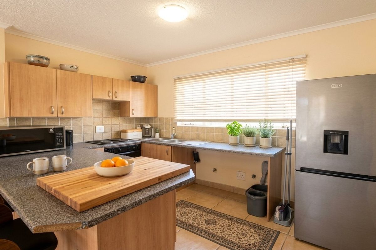 A functional kitchen featuring laminate cabinetry, granite countertops, tiled backsplash, and built-in cooking appliances with a breakfast bar area.