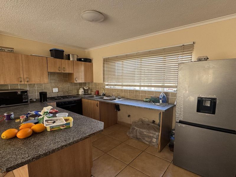 Functional kitchen featuring laminate cabinetry, granite countertops, tiled backsplash, and ceramic flooring, offering a practical layout with integrated cooking appliances.