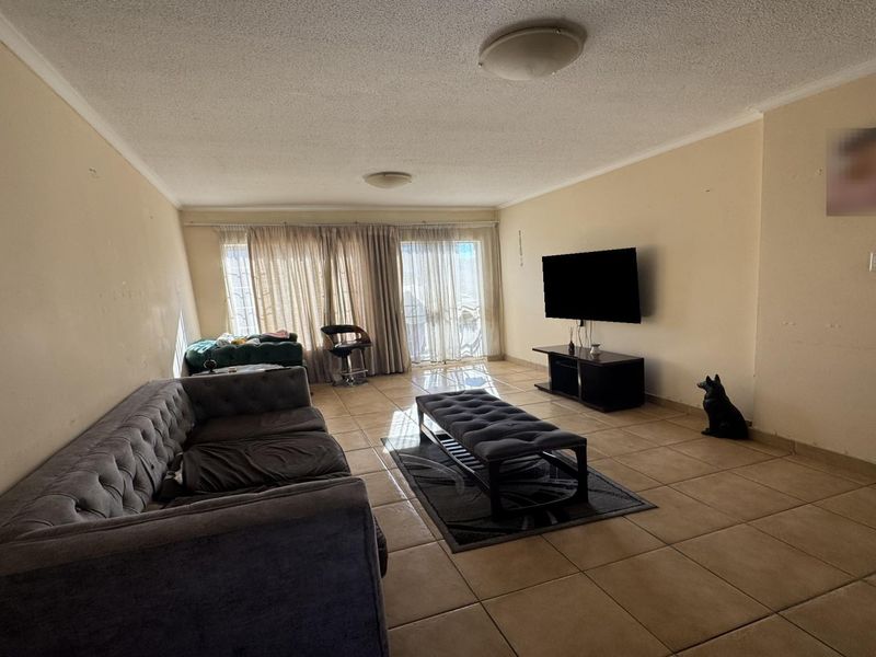 Spacious living room featuring tiled flooring, coved ceilings, and a large sliding glass door providing natural light and access to the exterior.