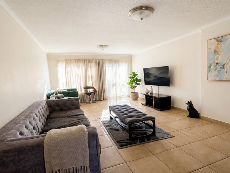 Spacious living room featuring neutral tiled flooring and large sliding glass doors that provide ample natural light.