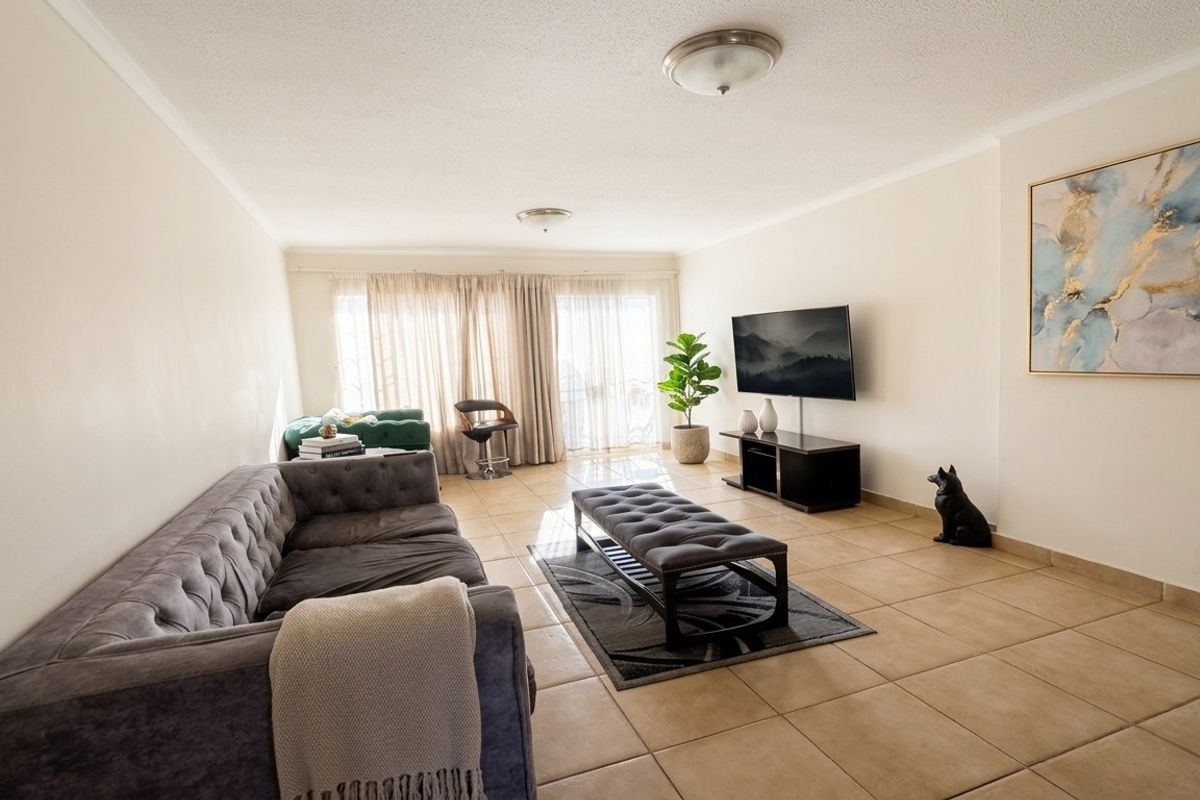 Spacious living room featuring neutral tiled flooring and large sliding glass doors that provide ample natural light.