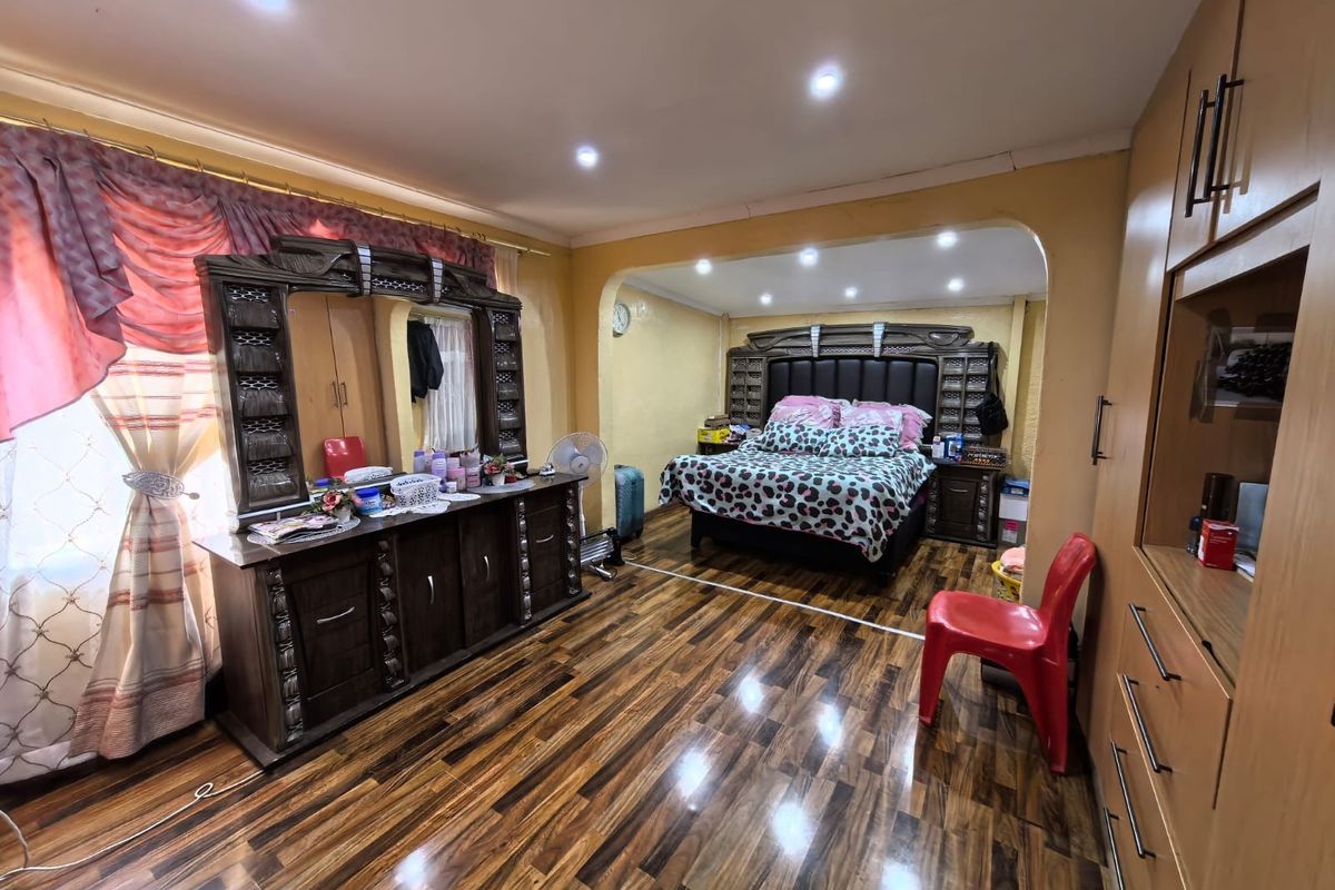 Spacious bedroom featuring polished laminate flooring, recessed ceiling lights, and extensive built-in cabinetry for storage.