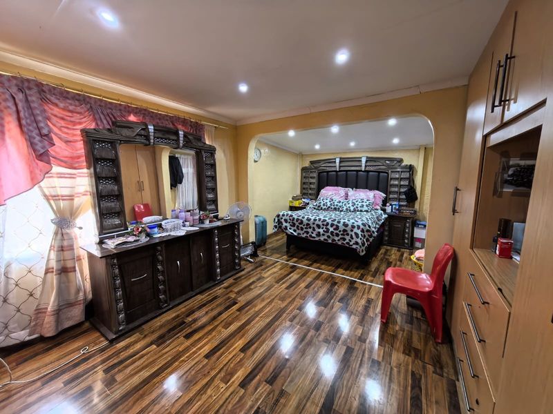 Spacious bedroom featuring polished laminate flooring, recessed ceiling lights, and extensive built-in cabinetry for storage.