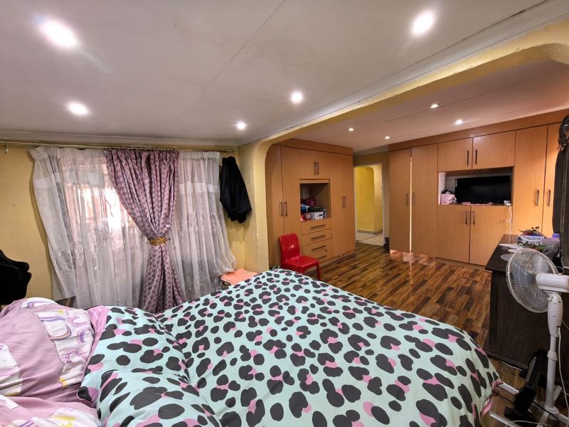 Spacious bedroom featuring extensive built-in wooden cabinetry, warm laminate flooring, and recessed ceiling lighting.
