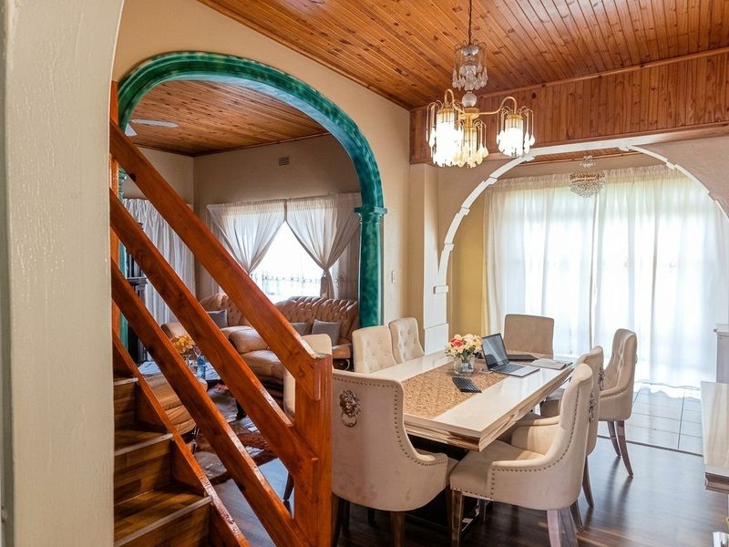 Open plan dining and living area featuring timber ceilings, decorative archways, and a staircase, creating a connected and traditional living space.
