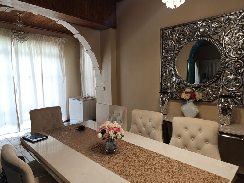 A formal dining room featuring a timber-paneled ceiling, decorative archway, and elegant crystal chandelier, creating a sophisticated space for entertaining.