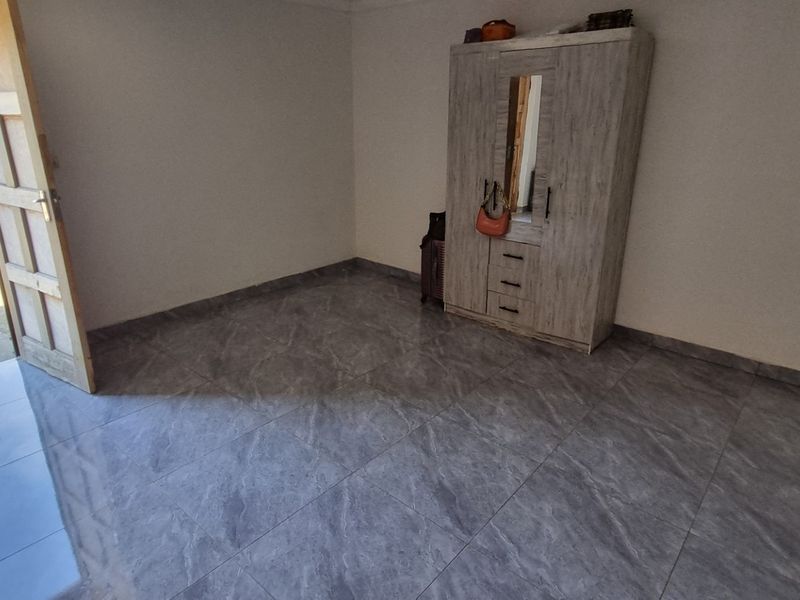 A living area featuring modern grey tiled flooring and direct access to the exterior through a timber door.