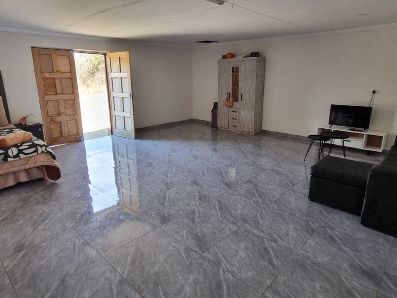 Spacious bedroom featuring large format grey tiled flooring and double wooden doors leading to the exterior.