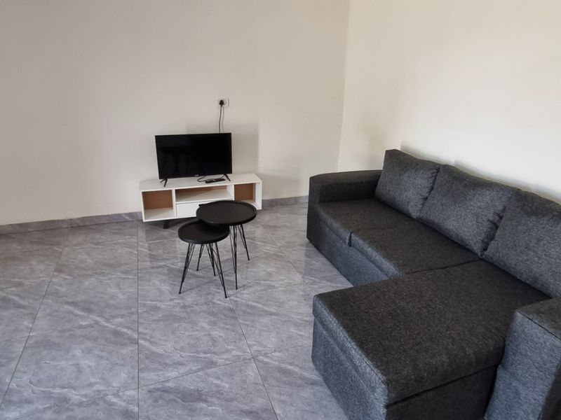 A living room featuring modern grey tiled flooring and a built-in cupboard, providing a clean and functional space.