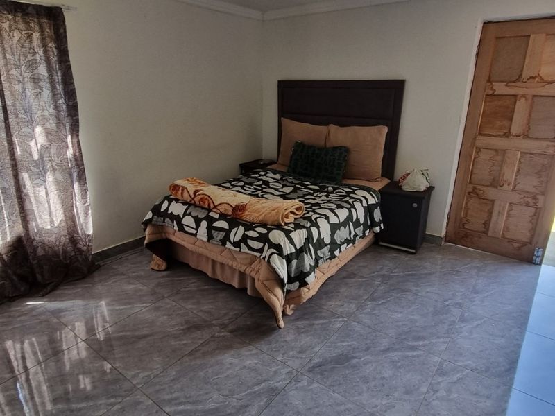 A bedroom featuring tiled flooring and direct access to the exterior through a wooden door.