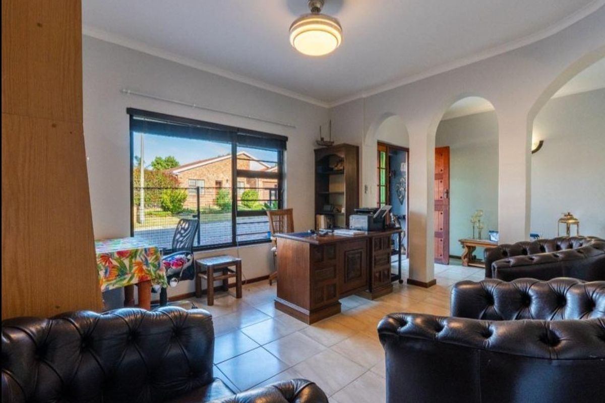 A living area featuring tiled flooring, arched architectural details, and a large window providing natural light.