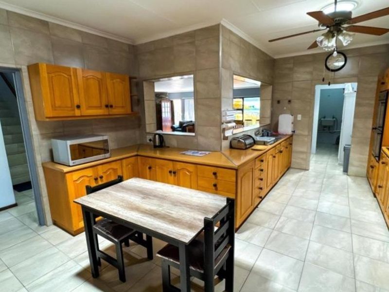 Spacious kitchen featuring extensive wooden cabinetry, tiled surfaces, and a functional layout with a central dining area and integrated appliances.