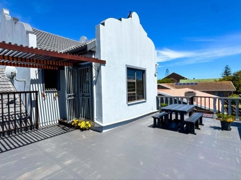 Spacious rooftop balcony featuring a wooden pergola, secure access gate, and classic balustrade railing, offering an open-air outdoor living space.