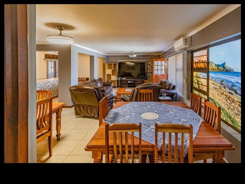 Spacious open-plan living and dining area featuring tiled flooring, ceiling fans, and a large window with scenic coastal views.