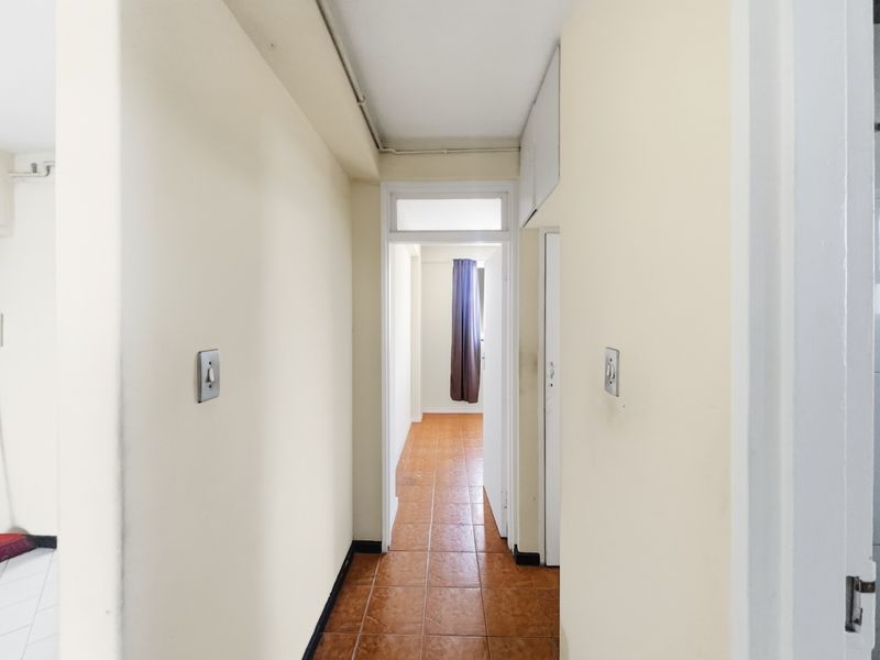 A functional apartment hallway featuring tiled flooring and neutral wall finishes, providing access to adjacent rooms.