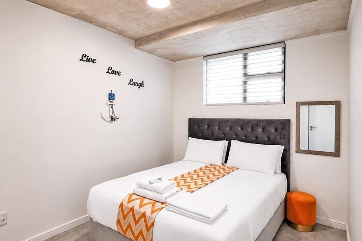 A compact bedroom featuring tiled flooring, a recessed ceiling design, and a window fitted with venetian blinds.