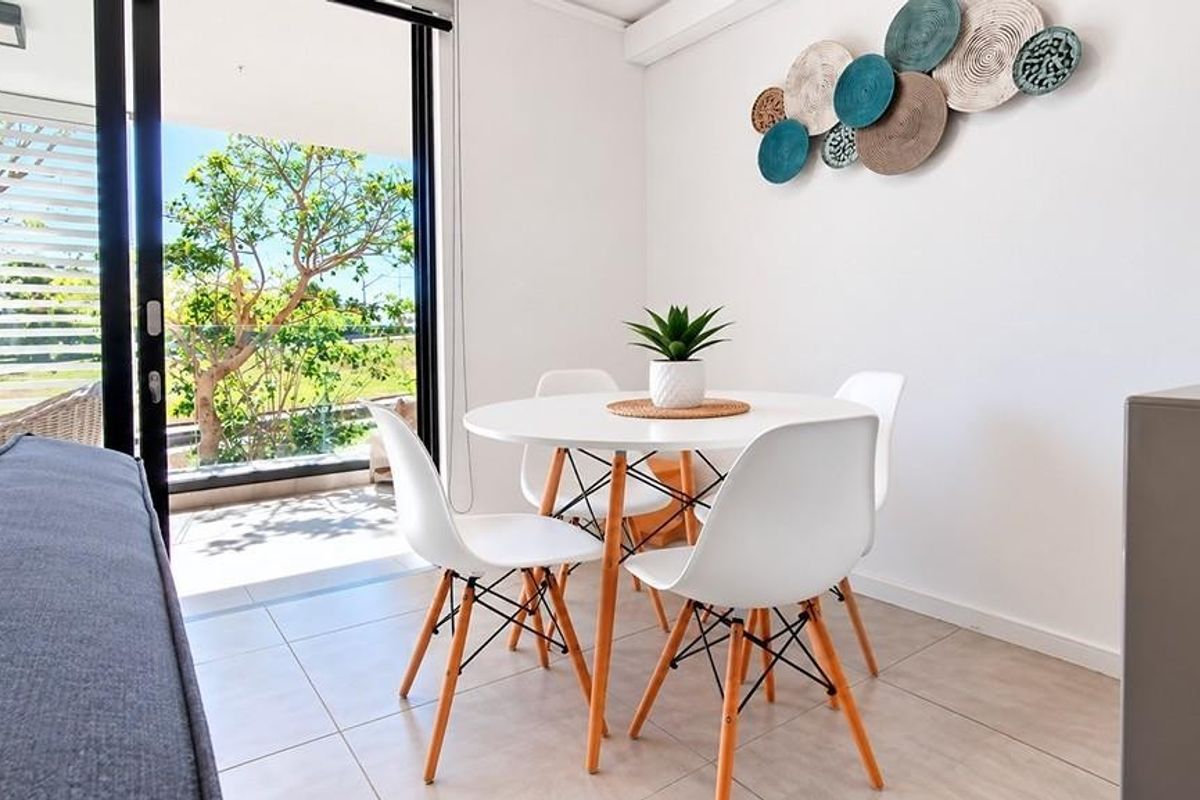 Bright living area featuring large sliding glass doors that open onto a balcony, complemented by neutral tiled flooring and modern recessed lighting.