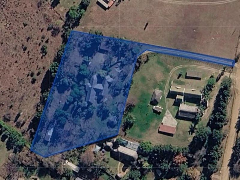 An aerial view showing the property boundary and surrounding land, including the main dwelling, outbuildings, and access driveway.
