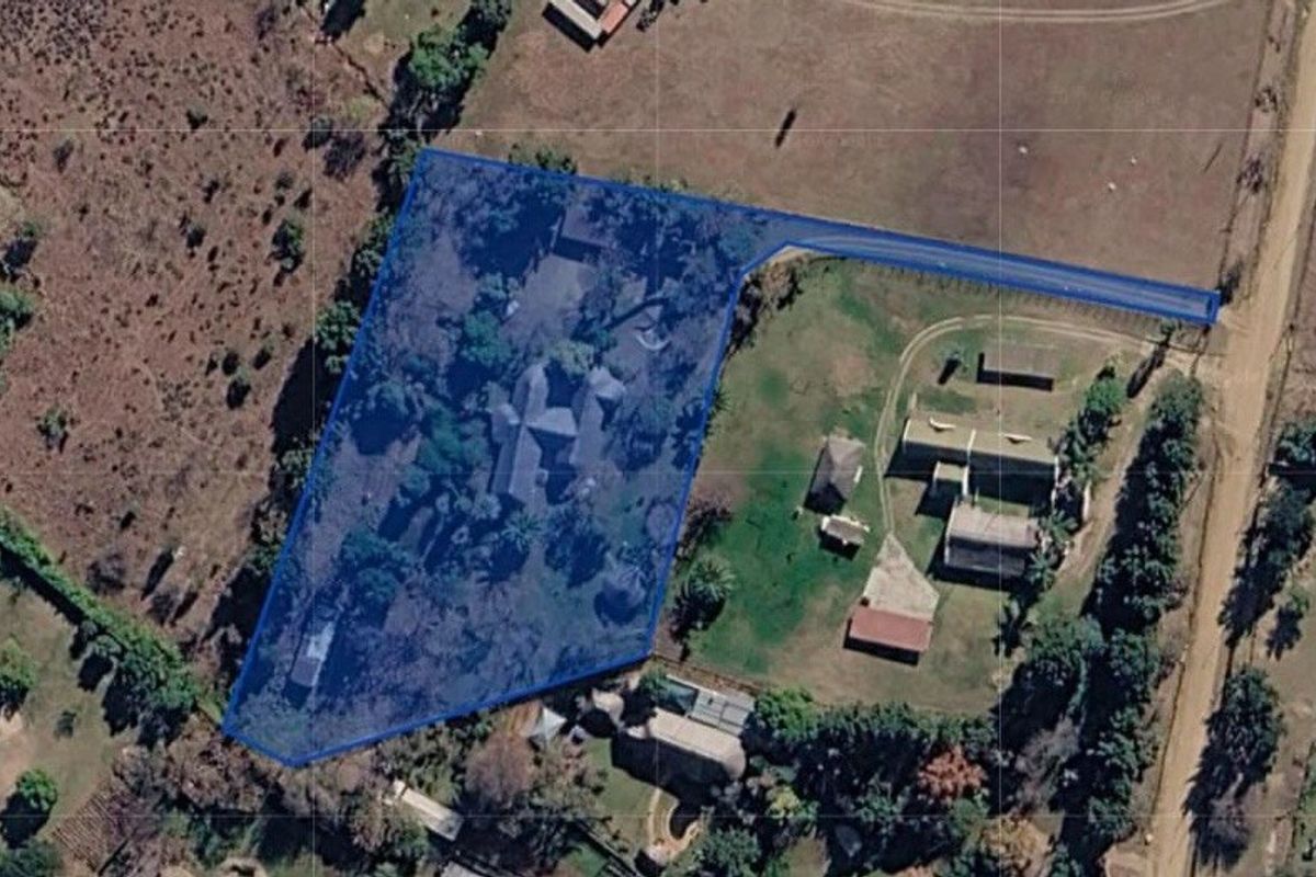 An aerial view showing the property boundary and surrounding land, including the main dwelling, outbuildings, and access driveway.
