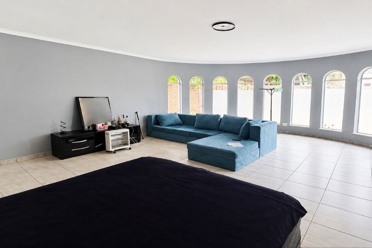 Spacious living room featuring large arched windows, neutral grey walls, and tiled flooring, offering a bright and open layout.