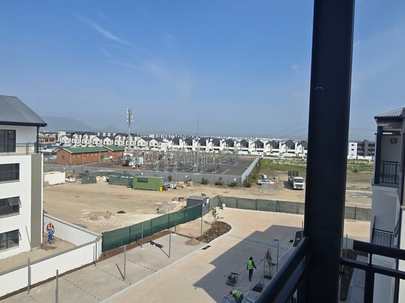 An elevated view from a balcony overlooking a residential apartment complex and surrounding development area.