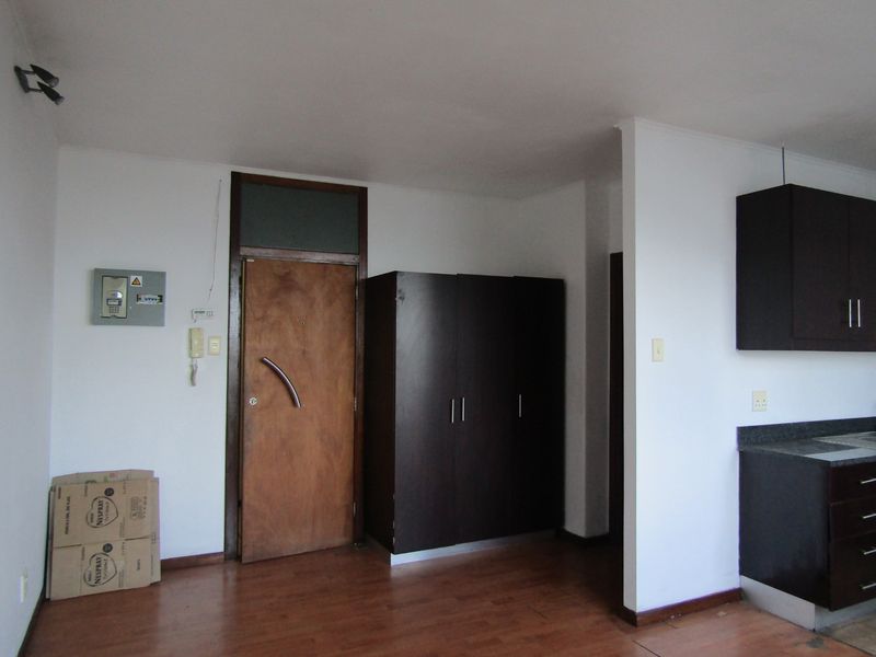 Open plan living area featuring laminate flooring, built-in storage cabinetry, and a secure entrance door with integrated intercom system.