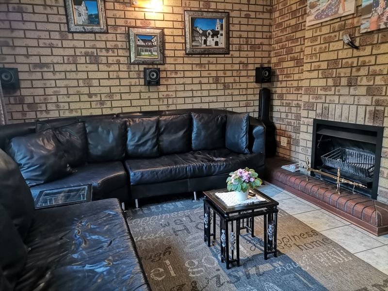 Cozy living room featuring exposed brick walls, a built-in brick fireplace, and tiled flooring, creating a rustic and warm atmosphere.